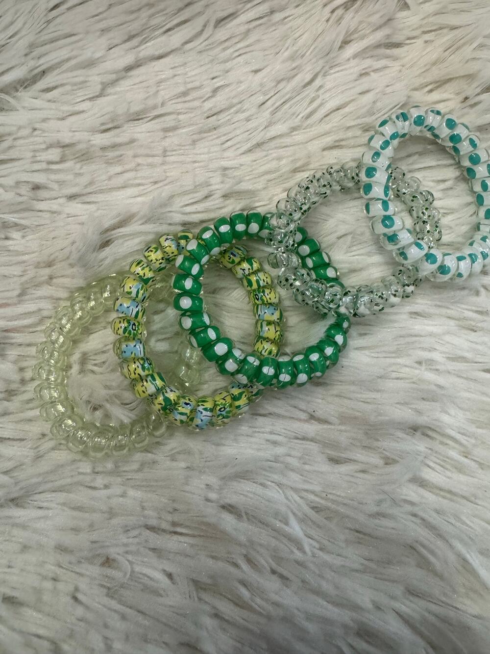 Green set of 5 coil spiral hair ties with polka dots and speckled patterns